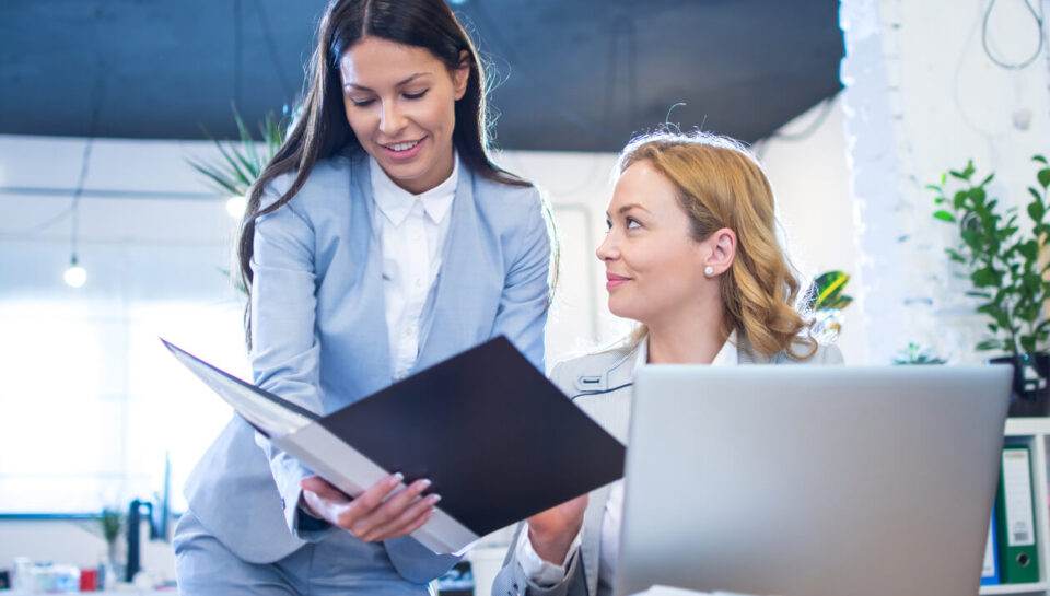 business-woman-showing-paper-documents-her-older-female-colleague-office