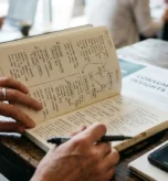 Badacz rynku z notatnikiem pełnym odręcznych notatek terenowych i schematów zachowań konsumentów, obok raportu Consumer Insights i nagrywającego smartfona — dokumentacja z badania etnograficznego w naturalnym środowisku.