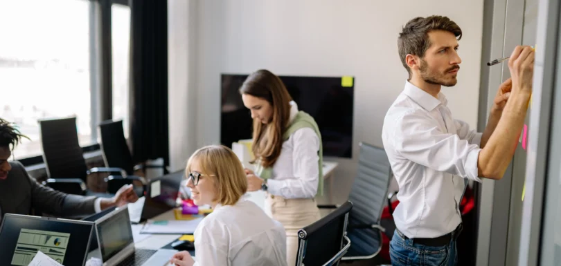 Jak zbadać otoczenie konkurencyjne przedsiębiorstwa B2B - alternatywy dla SWOT i wywiad rynkowy w praktyce 1 Zespół badawczy planuje projekt przy ścianie z karteczkami i laptopach z danymi - badanie rynku niszowego B2B